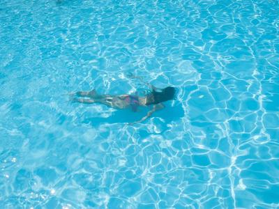 Eine Person schwimmt entspannt in klarem, blauem Wasser eines Pools.