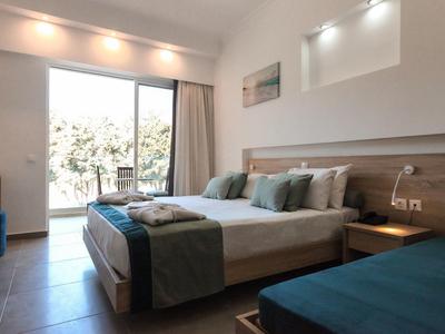 Modernes Hotelzimmer mit Doppelbett, Terrasse und schlichter Einrichtung in neutralen Farben.