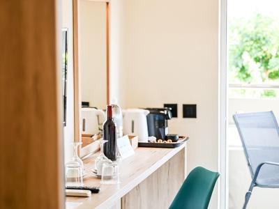 Moderner Arbeitsbereich mit Schreibtisch, grünem Stuhl und Kaffeemaschine neben offenem Balkon.