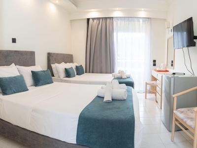 Helles Hotelzimmer mit zwei Einzelbetten, grauen Kopfstützen und blauweißer Bettwäsche.