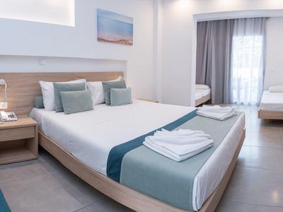 Modernes Hotelzimmer mit großem Bett, Nachttischen und Balkon mit Vorhängen.