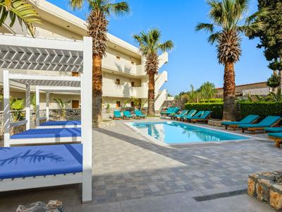 Moderne hotelzwembad met ligbedden, palmbomen en zonbescherming bij heldere lucht.