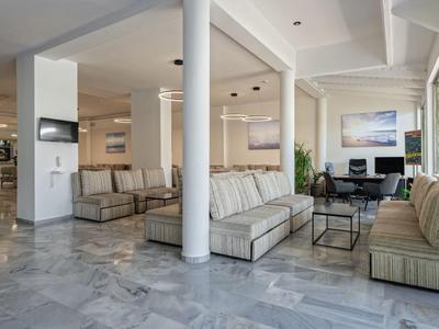 Lichte hotel lounge met moderne zitmeubels en marmeren vloer.