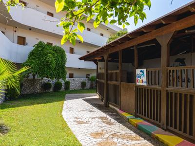Cortile di un hotel con padiglione di legno, prato e edificio bianco sullo sfondo.
