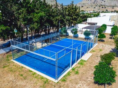 Campo da paddle blu con recinzione e alberi sullo sfondo.