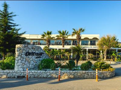 Un hotel con palme e un ingresso ben curato sotto un cielo azzurro limpido.