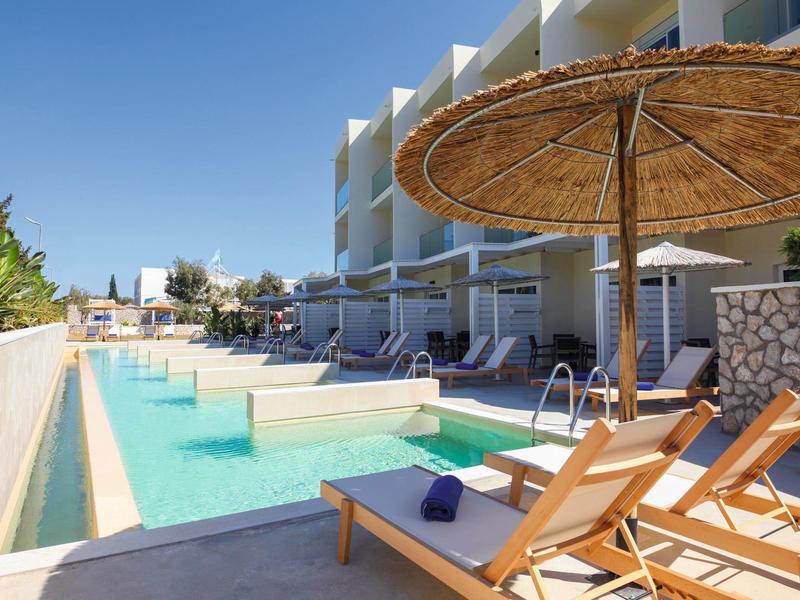 Moderner Hotelpool mit Liegestühlen, Sonnenschirmen und direktem Zugang zu den Zimmern.