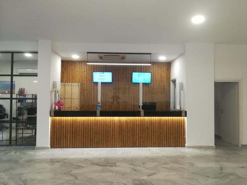 Moderner Empfangstresen mit Holzverkleidung und zwei Monitoren in einem hellen Raum.