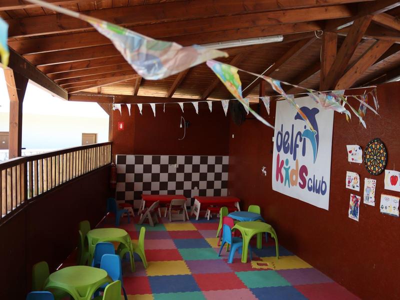 Bunter Kinderspielbereich mit kleinen Stühlen und Tischchen, dekoriert mit Wimpelkette und Wandbildern.