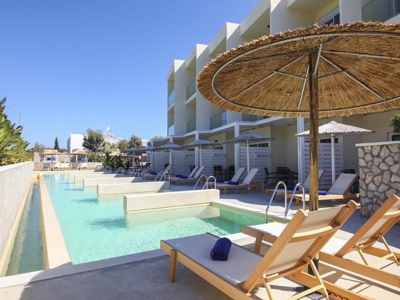 Moderner Hotelpool mit Liegestühlen, Sonnenschirmen und klarem Himmel im Hintergrund.