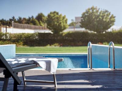 Lounge chair with towel by a calm pool with green surroundings.