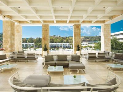 Bright terrace with comfortable sofas overlooking water and boats.