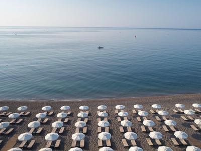 Reihe von Liegestühlen mit Sonnenschirmen am ruhigen Strand mit klarem Himmel.