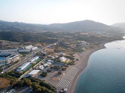 Aerial view of a coastal resort with sandy beach and surrounding hills.