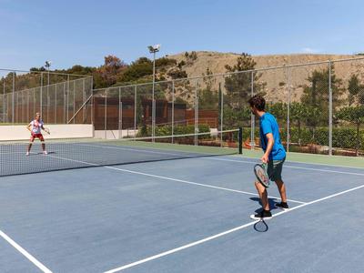 Zwei Personen spielen Tennis auf einem Außenplatz mit Berg im Hintergrund.