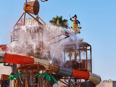 Water park with water slides and a large bucket dumping water onto a platform.