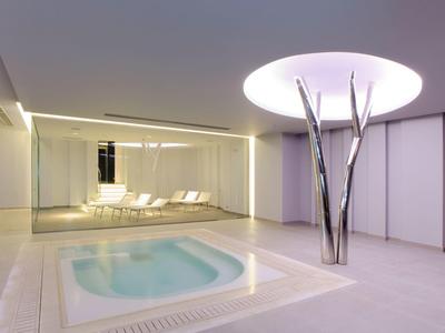 Modern spa area with jacuzzi, lounge chairs, and creative ceiling light design.