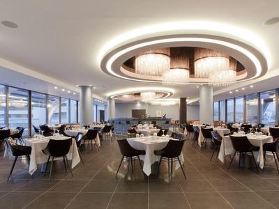 Modern elegant restaurant with large round tables and stylish ceiling lighting.