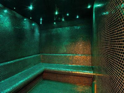 Sauna lounge with green mosaic tiles and dim ceiling lights.