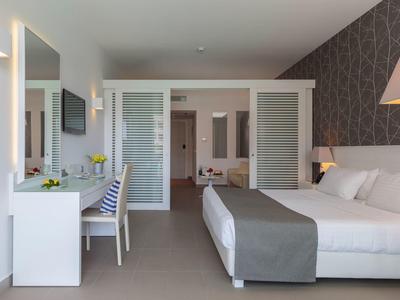 Modern hotel room with double bed, desk, and cozy lighting.