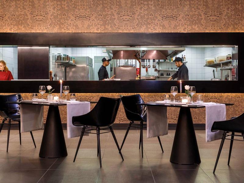 Modern restaurant with small tables, candles, and black chairs as decoration.