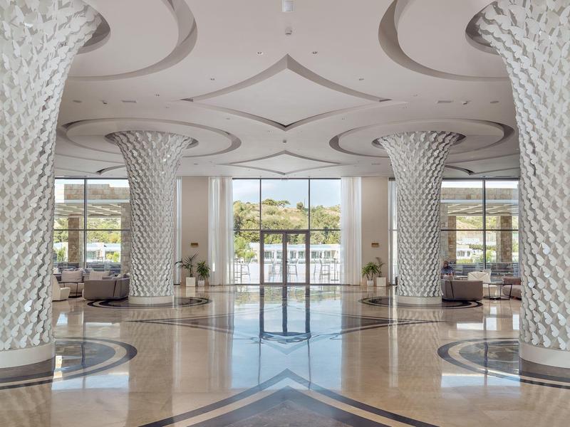 Spacious, elegant hotel lobby with artistic columns and large windows offering an outside view.