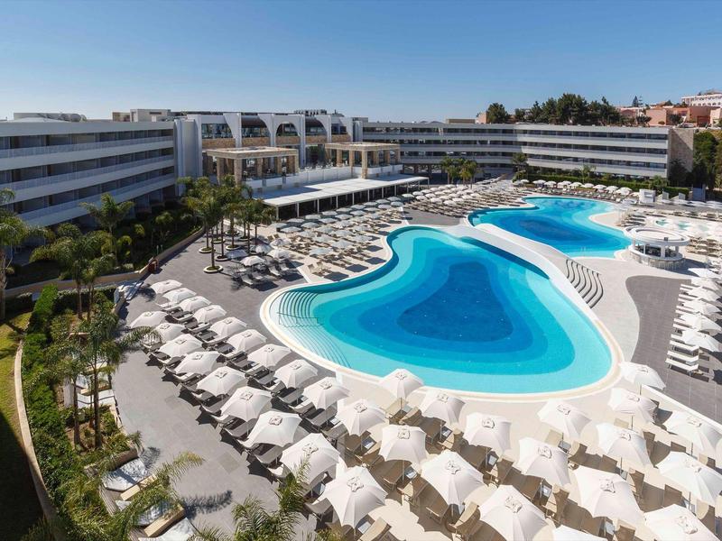 Large hotel pool with numerous sun loungers and clear blue water.