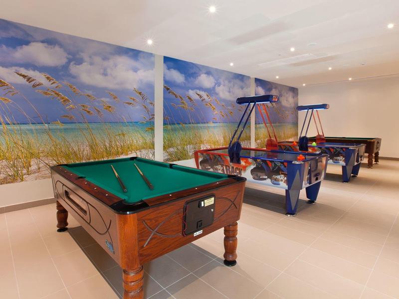 Game room with pool table, foosball, and ping pong in front of a beach mural.