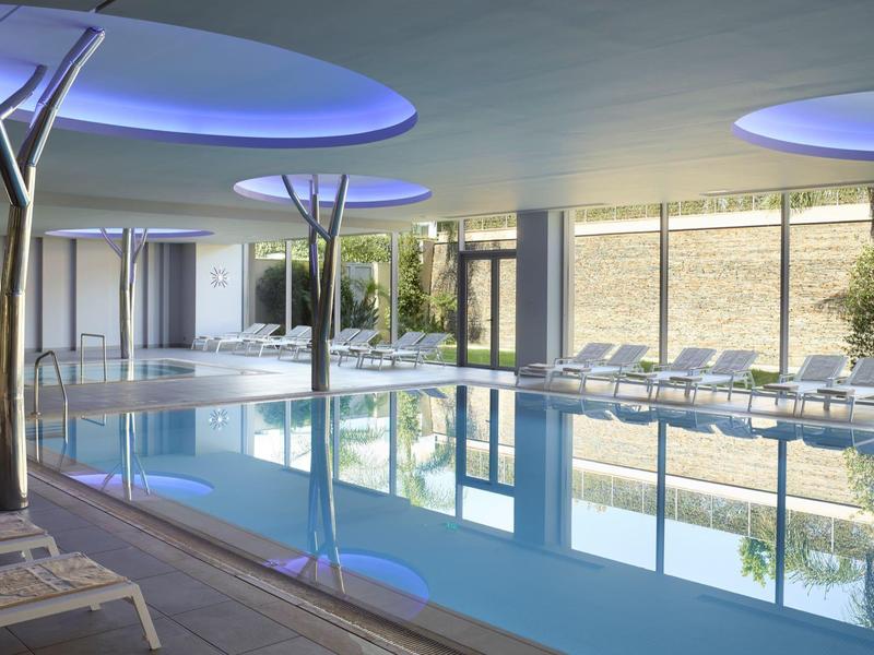 Bright, modern indoor pool with lounge chairs and large windows.
