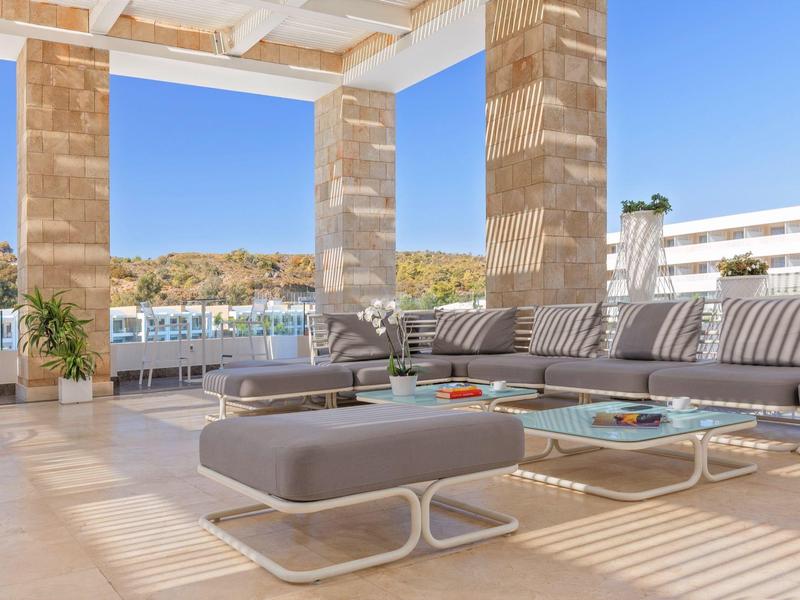 Bright terrace with comfortable seating and a view of water and hills.