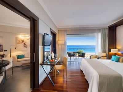 Camera d'hotel moderna con letto matrimoniale, balcone e vista sul mare.