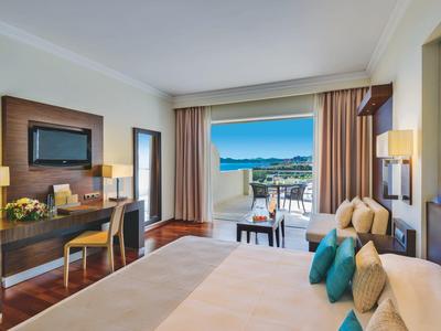 Camera d'albergo luminosa con balcone e vista sul mare, arredamento moderno.