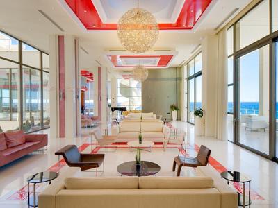 Ampio salone d'hotel con arredamento moderno e vista sul mare da grandi finestre.