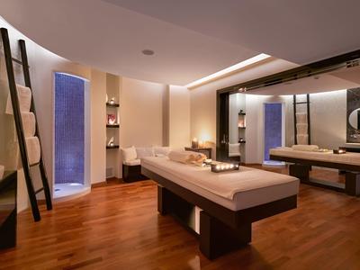 Sala massaggi elegante con tavolo centrale, pareti beige e pavimento in legno.