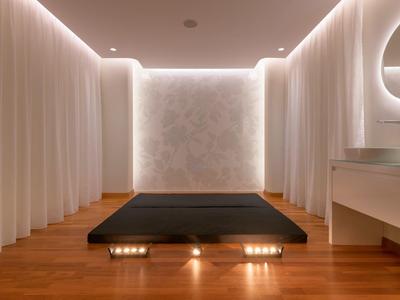 Camera d'hotel minimalista con letto basso e tende bianche che circondano la stanza.