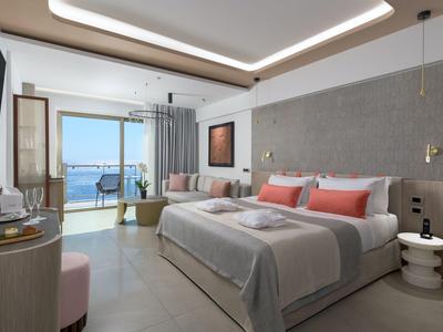 Modernes Hotelzimmer mit großem Bett, Balkon und Meerblick, hell und stilvoll eingerichtet.