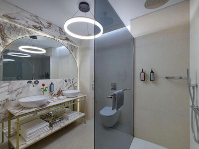 Modernes Badezimmer mit zwei Waschbecken, Glasdusche und großen runden Spiegeln.