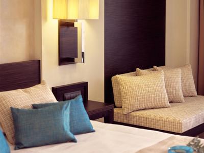 Modern eingerichtetes Hotelzimmer mit großem Bett, Sofa und warmem Licht.