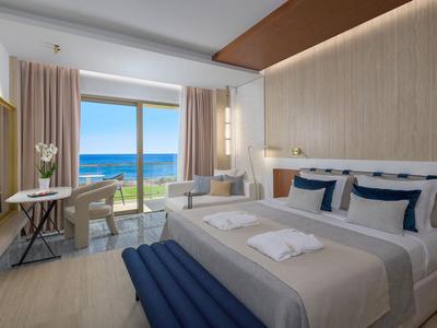 Modernes Hotelzimmer mit Meerblick, Doppelbett, Sitzecke und Zugang zum Balkon.