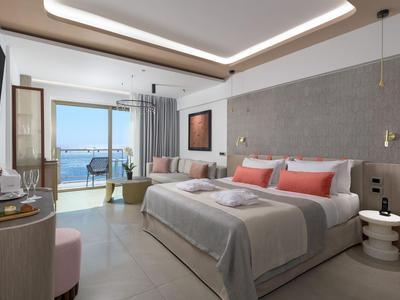 Modernes Hotelzimmer mit Doppelbett, Balkon und Meerblick, in hellen, neutralen Farben.