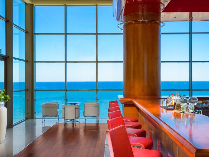 Bar elegante con vista panoramica sul mare attraverso grandi finestre.
