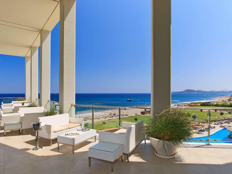 Terrazza con mobili bianchi con vista sul mare e piscina sotto un cielo limpido
