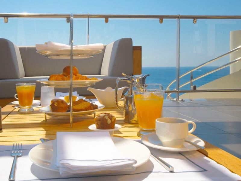 Colazione su una terrazza con vista mare, bevande e pasticceria.