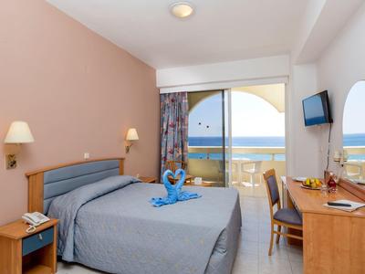 Camera d'hotel con letto matrimoniale, scrivania, balcone e vista mare.