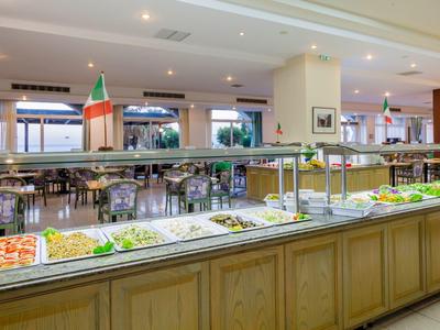 Buffet nella sala da pranzo con vari piatti e bandiera italiana come decorazione.