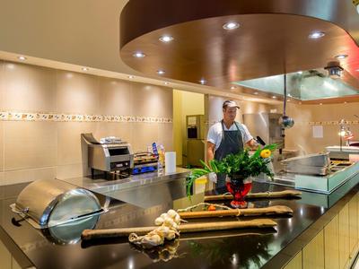 Cucina d'hotel moderna con stazione di cottura, spezie e chef al lavoro.