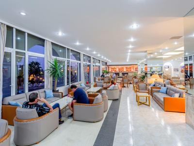 Lounge dell'hotel luminosa con grandi finestre, aree salotto e ospiti rilassati la sera.