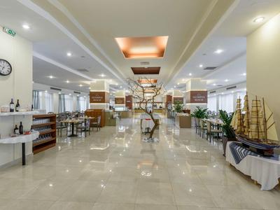 Ampio ingresso dell'hotel con pavimento lucido, decorazioni marittime e illuminazione moderna.