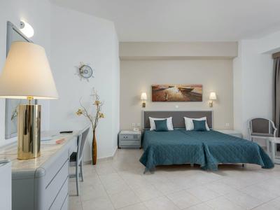 Camera d'hotel luminosa con due letti singoli, copriletto blu e arredamento moderno.