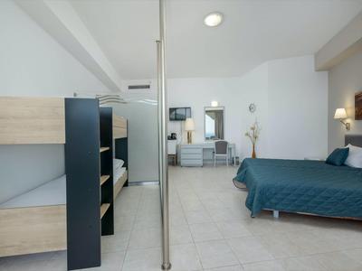 Camera d'hotel luminosa con letto a castello, letto singolo, area salotto e design moderno.